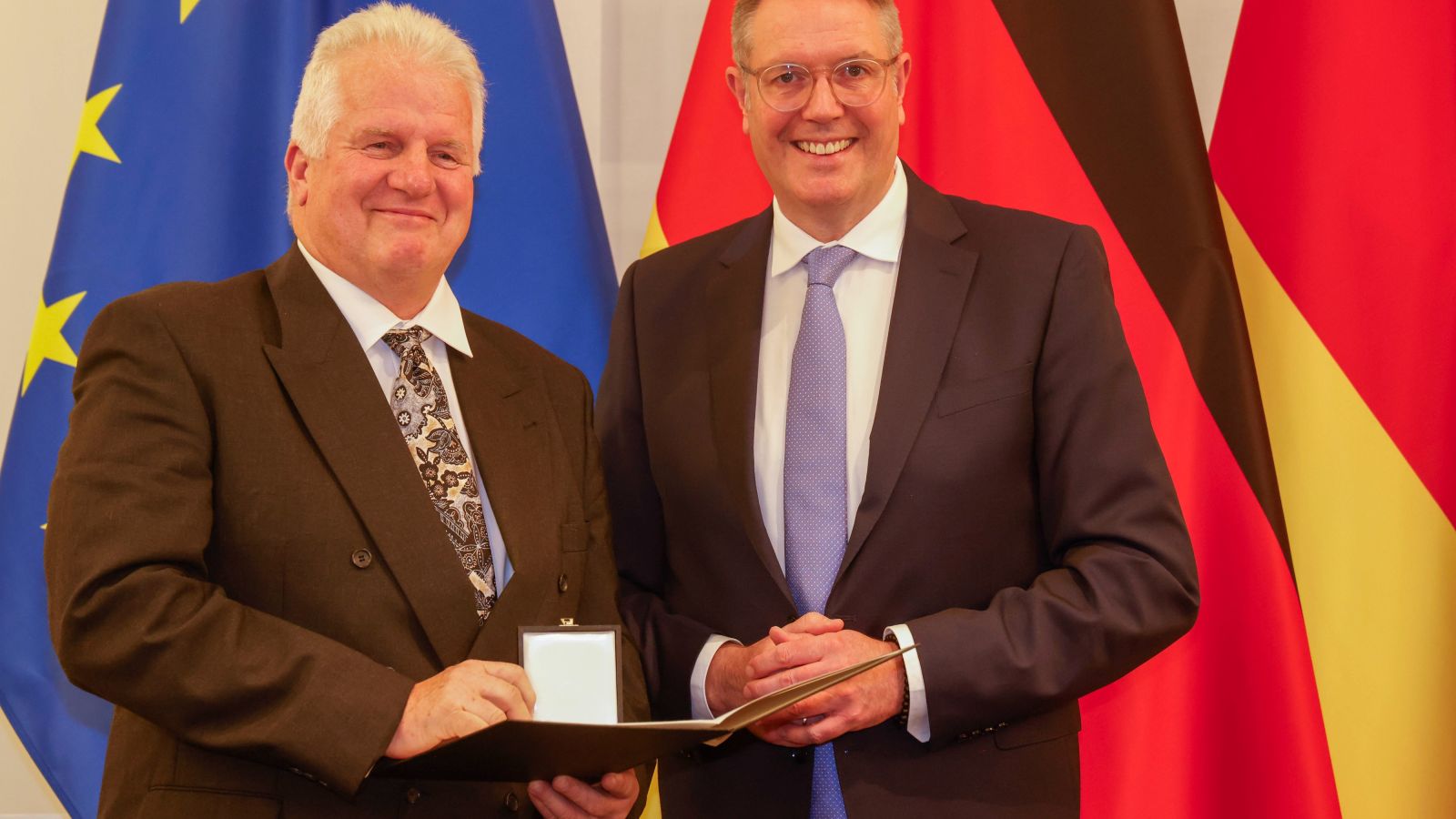 Klaus Kaiser nimmt den Landesverdienstorden des Landes Rheinland-Pfalz aus den Händen von Ministerprädient Alexander Schweitzer entgegen. 